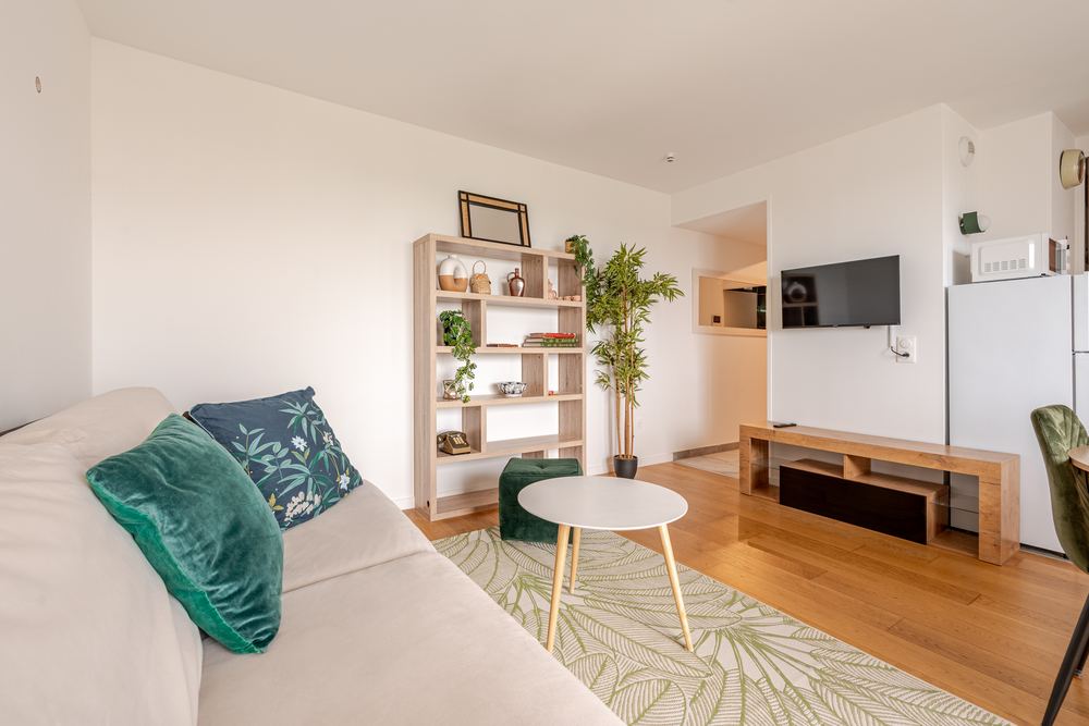 Living room with sofa, open shelving and wall-mounted TV